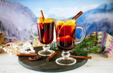 Mulled wine with spices and Christmas decoration on a wooden table against the background of a winter mountain landscape
