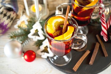 Mulled wine with spices and Christmas decoration on a wooden table against the background of a winter mountain landscape