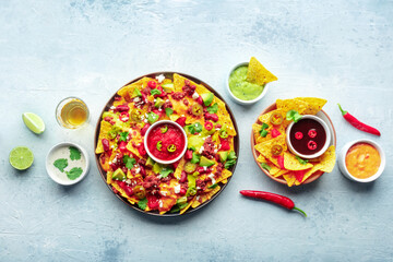 Loaded nachos. Mexican nacho chips with beef, overhead flat lay shot with guacamole sauce, cheese...