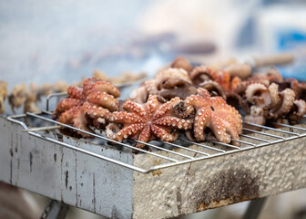 Octopus with long tentacles grilled on a metal grill at a seafood restaurant in Italy