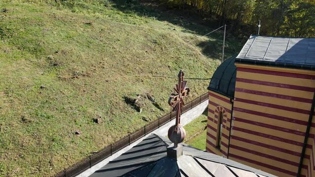Drone flies around decorative metal cross on top of building in monastery Ribnica