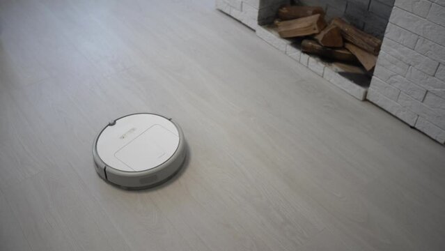 Robot vacuum cleaner vacuuming the floor in the bedroom. Smart home with automated devices that simplify life. A smart vacuum cleaner cleans the floor.