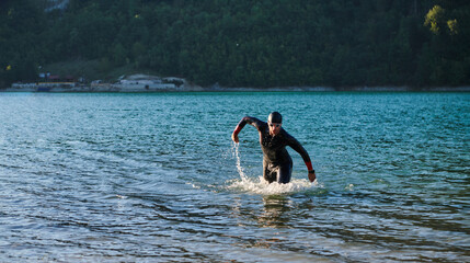 Triathlon athlete starting swimming training on lake