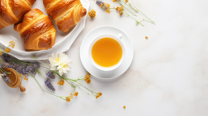 Obraz na płótnie Canvas Beautifully arranged breakfast setting with golden-brown croissants, a cup of tea, and vibrant orange flowers on a light background.