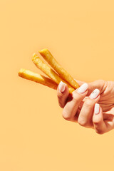 Female hand with tasty french fry on color background