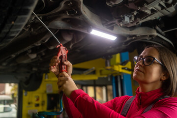 Female auto mechanic work in garage, car service technician woman check and repair customer car at...