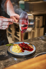 The chef pours berry sauce on leg of lamb with mashed potatoes