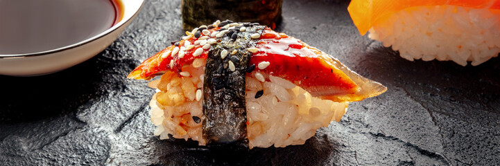 Unagi sushi, nigiri with eel, panorama with soy sauce on a black background. Japanese restaurant
