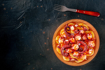 Pulpo a la gallega, Spanish octopus snack, Galician dish, top shot on a black slate background with a place for text
