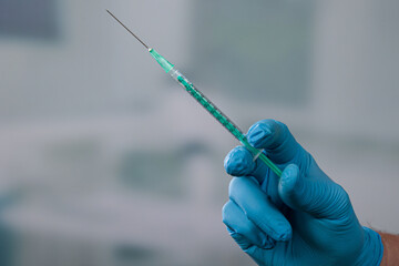 Close up of doctor's or nurse's hand in medical gloves with a syringe with vaccine in front of a...