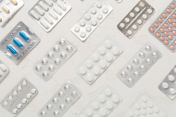 Pills in blister packaging on concrete background, top view