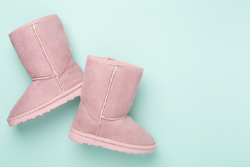 Beautiful childish ugg boots on color background,top view