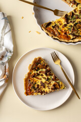 Portion of pie on a plate, homemade quiche with seasonal forest mushrooms Chanterelles on a yellow background