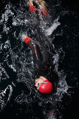 A determined professional triathlete undergoes rigorous night time training in cold waters,...