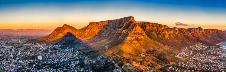 cape town aerial panorama from the table mountain at sunset, sun shining on the mountain range town in the dusk