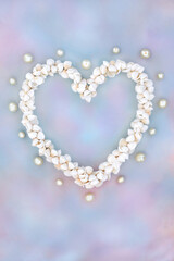Heart shaped cockleshell wreath with oyster pearls on rainbow sky cloud background. Symbol of nature sea life summer love. Greetings card for Valentines, birthday, mothers day or anniversary.