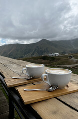 Drinking coffee outdoors. Two cups of coffee on a wooden table in a cafe. Coffee shop in the...