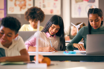 Secondary Or High School Students Studying Wind Turbines In Science Class With Teacher In Background