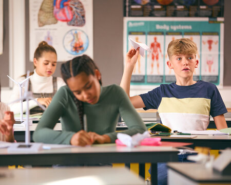 Disruptive Male Secondary Or High School Student Throwing Paper Dart In Science Class 