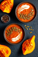 Plates with creamed pumpkin soup, pumpkin seeds and sliced pumpkins 