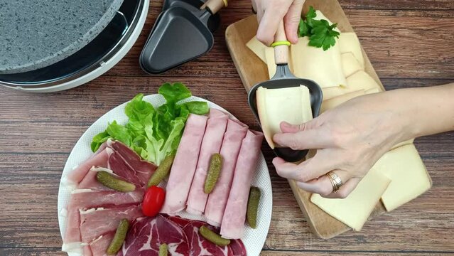 gros plan d'une personne mettant un fromage &agrave; raclette en cuisson dans un appareil &agrave; raclette