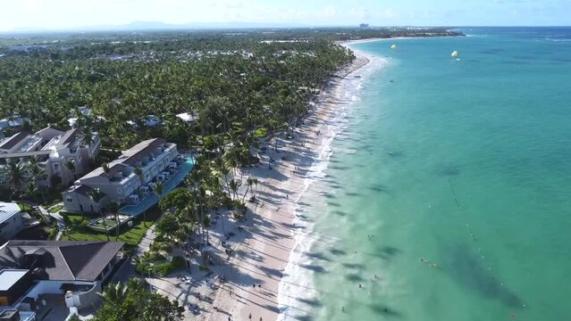 Wakacyjna plaża z palmami na karaibach, a obok turkusowy ocean z delikatnymi falami. Jest to nadmorski kurort turystyczny.