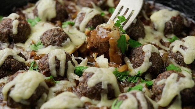 Eating French onion beef meatballs with fork