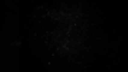 Silver glitter flying after being exploded, bright sparkles bouncing against camera flying and falling down on black background. Top view close up macro slow motion - Powered by Adobe