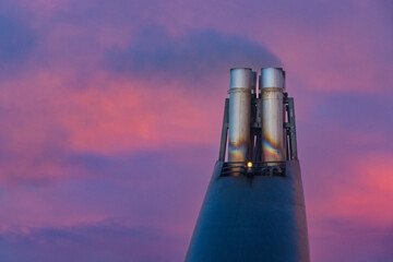 Big metallic funnel in the stern of a ship with smoke and pink sunset in the Atlantic Ocean Ferry