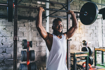 Muscular black sportsman lifting heavy barbell in gym - obrazy, fototapety, plakaty