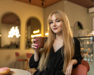 Portrait of a young beautiful blonde girl in a cafe.