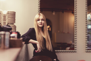 Portrait of a young beautiful blonde girl in a cafe.