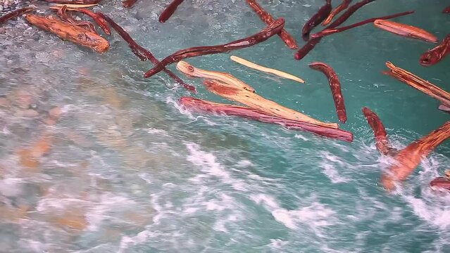 The flow of water carries the logs into the funnel. A stormy river washes away a forest, a flood.