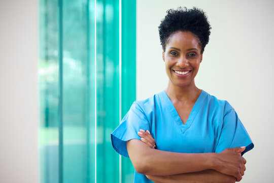 Portrait Of Mature Smiling Female Doctor Wearing Scrubs In Hospital With Copy Space
