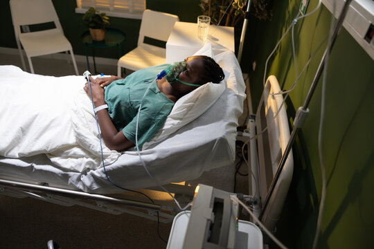 Image of a woman, African, in a hospital room, with an oxygen mask, recuperating after a severe asthma attack.