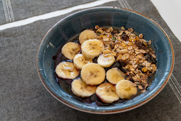 a bowl of healthy acai ice cream topped with banana oats and honey. 