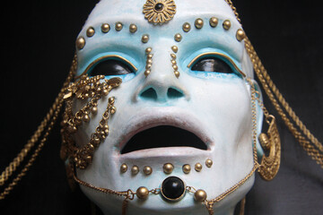 Face of the blue statue. Detail of alien face with black ball eyes, decorated with gold ornaments....
