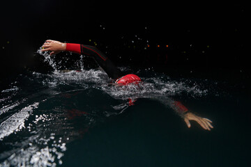 A determined professional triathlete undergoes rigorous night time training in cold waters,...
