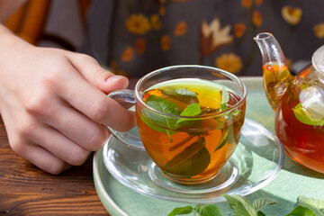 The girl holds in her hand a cup of green tea with mint. Healthy food, antioxidants.