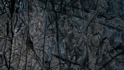 A rough rocky texture with cracks, stains and wholes on displaced surface of stone - obrazy, fototapety, plakaty