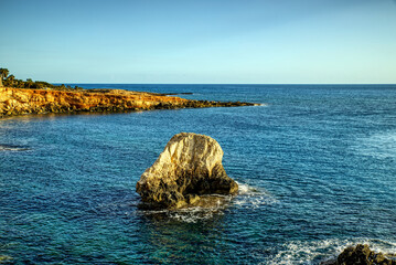 Sea caves en beautifful rocky Cypriot coast, brightly blue water, sunny day with blue sky