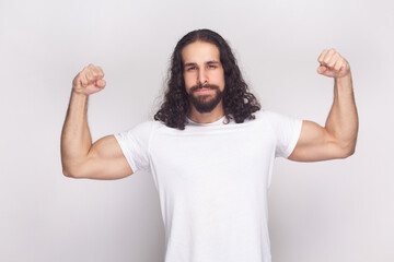 Portrait of strong powerful bodybuilder man in white t-shirt with long wavy hair and beard,...