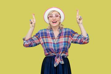 Portrait of mature woman wearing checkered shirt, hat and eyeglasses points above, recommends to...