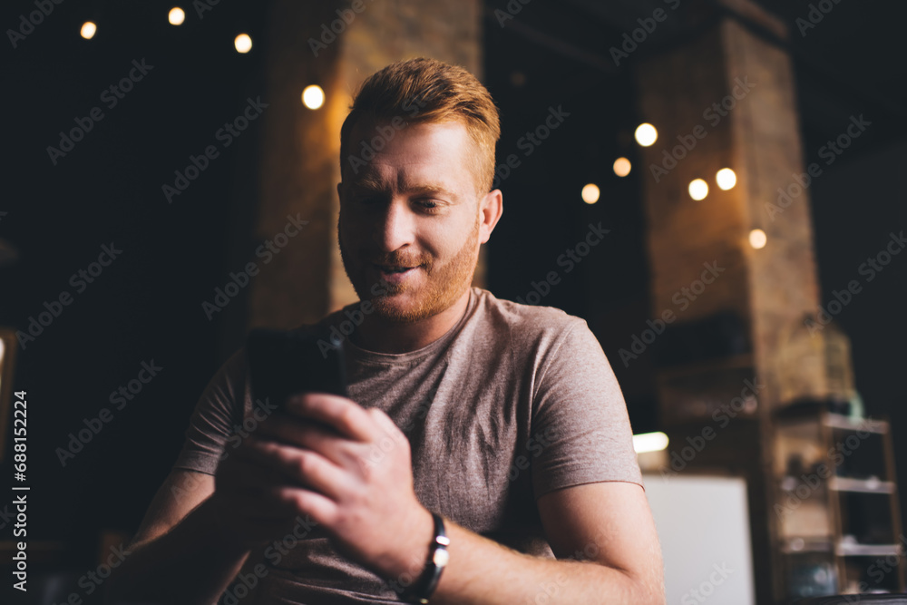 Poster male blogger installing application while connecting to 4g wireless internet on modern mobile phone