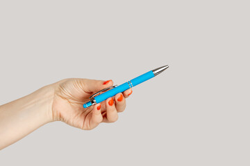Closeup of woman hand holding blue ballpen writing empty space for advertisement. Indoor studio shot isolated on gray background.
