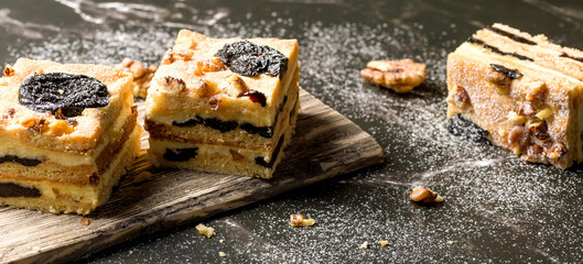 Cake with prunes and nuts. Pieces of delicious cake on a wooden plate. Decoration for the New Year...
