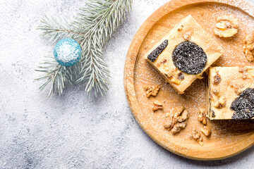 Cake with prunes and nuts. Pieces of delicious cake on a wooden plate. Decoration for the New Year and Christmas table. Flat lay. Copy space