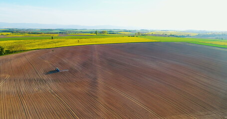 Farmer using tractor to spray field before planting.