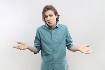 Portrait of uncertain puzzled confused attractive young man standing spread arms, shrugging...