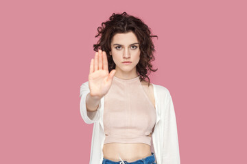 Portrait of strict bossy woman with curly hair wearing casual style outfit showing stop gesture...